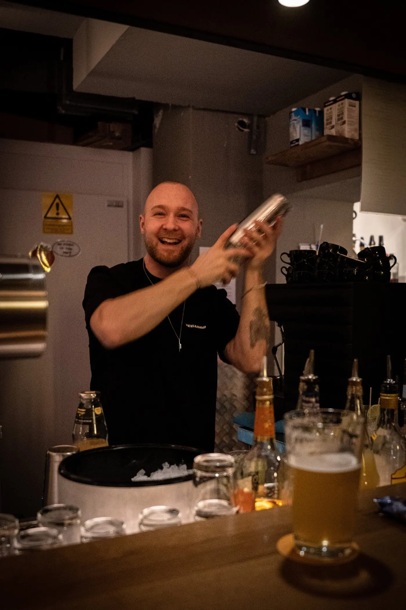 Ein Barkeeper schüttelt lachend einen Cocktail hinter der Theke